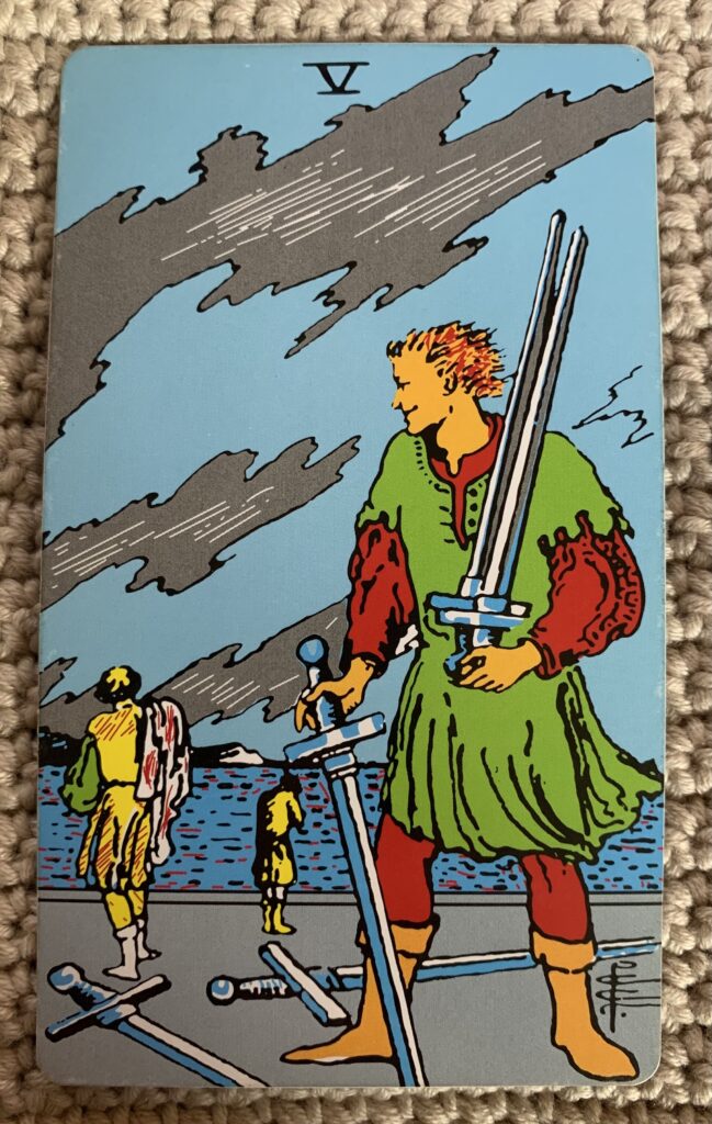 A man picking up 3 swords looks back at two other men with an odd smile on his face. Two more swords lay on the ground while one man looks toward the other who stands closer to a large body of water appearing to hold his head in his hands. Sketchy grayish clouds appear in a blue sky.